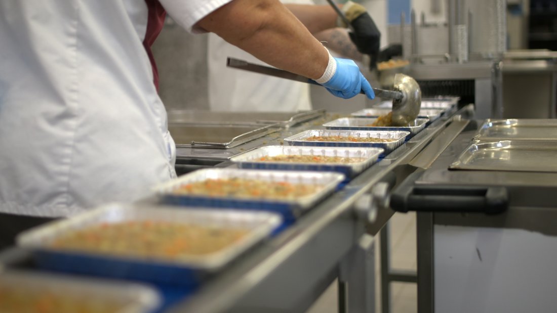 Food trays moving along a stainless conveyor