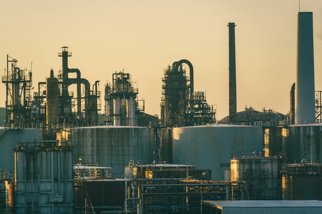Refinery with storage tanks and pipework at sunset