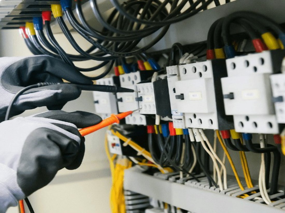 Engineer testing a control panel's contactors with a multimeter